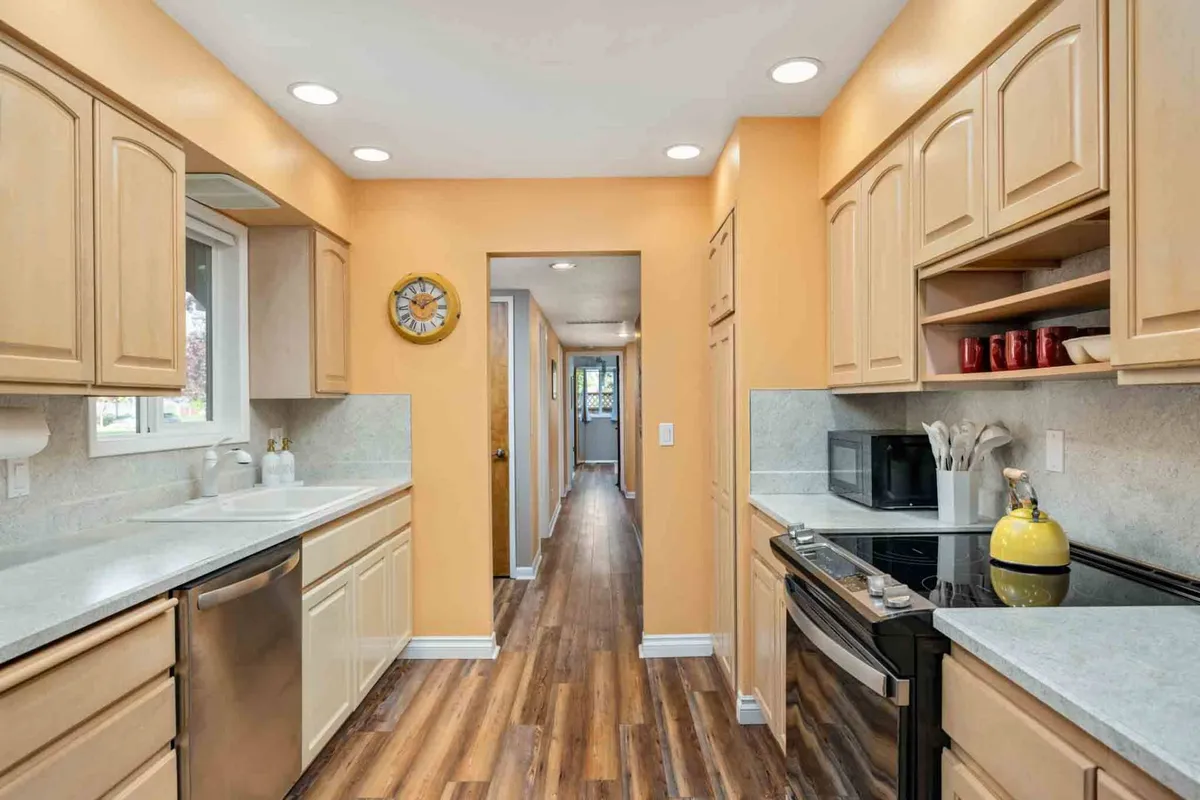 This image showcases a spacious, inviting kitchen with prominent kitchen cabinets, sleek stainless steel appliances, ample counter space, and cheerful yellow accents. The scene is set up for cooking, family gatherings, and guest entertainment, perfectly illustrating the heart of the home.