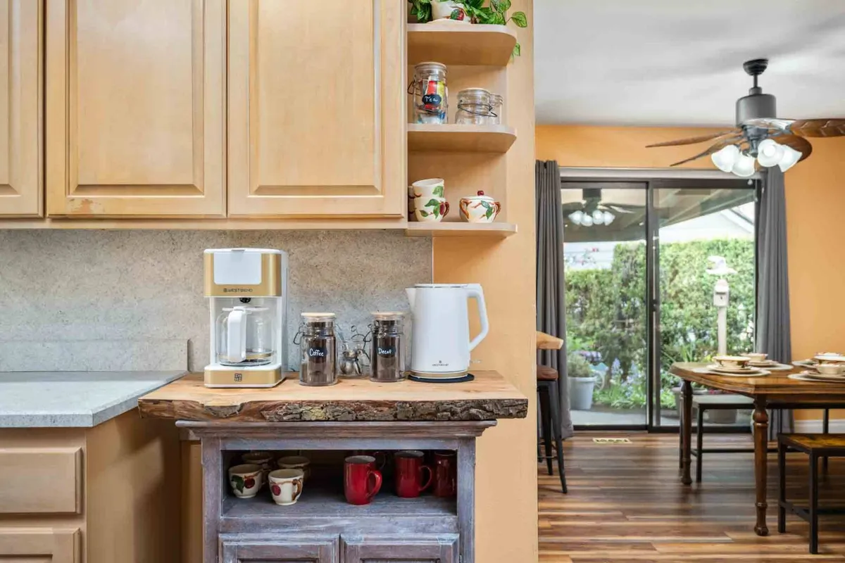 This image highlights a welcoming nook of the kitchen, featuring a coffee maker, kettle, decorative mugs, and a wooden countertop. The mood is cozy and intimate, suggesting moments of brewing coffee, casual dining, and socializing.