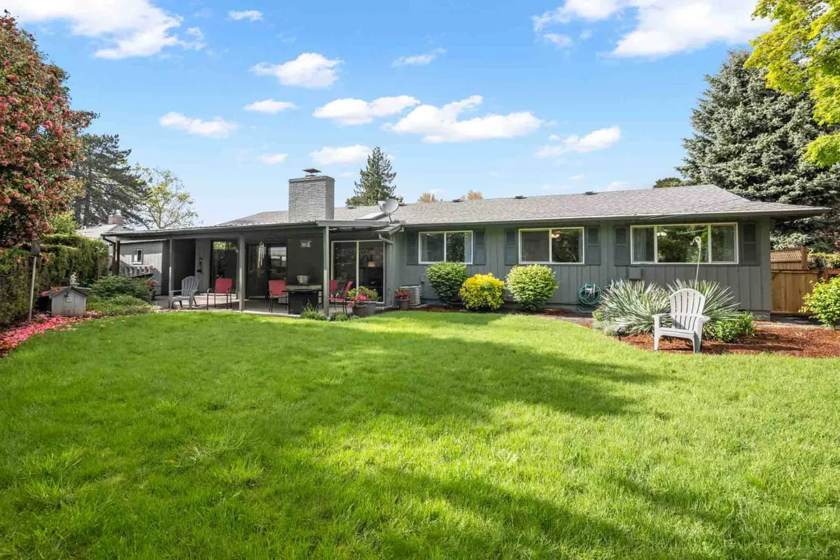 This image captures the exterior of the home, featuring a lush green lawn and a welcoming patio seating area. The scene hints at a peaceful setting, ideal for families to relax while children and pets play safely in the fenced yard. The house exterior is visible, showcasing the connection between indoor and outdoor spaces.
