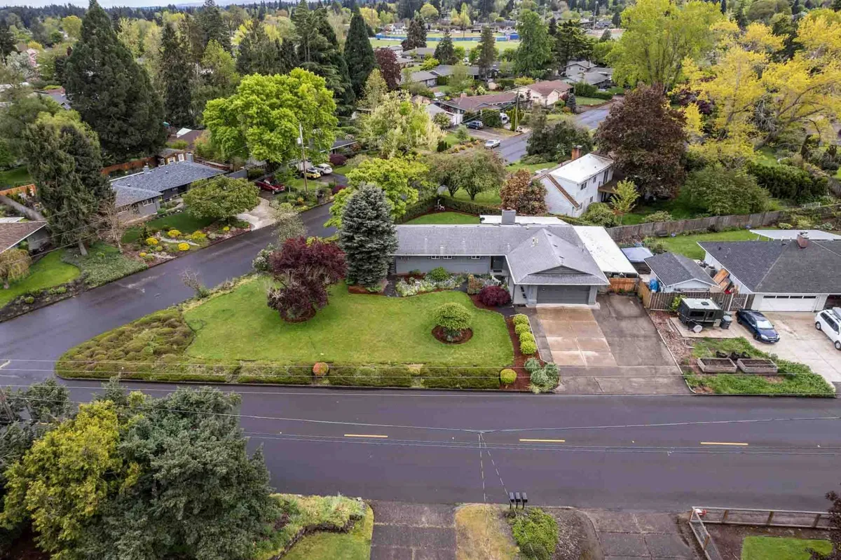 A wide shot of a lush green lawn bordered by colorful shrubs and mature trees. The neat driveway and well-tended landscaping create an inviting, peaceful outdoor environment, suggesting both privacy and a connection with nature.
